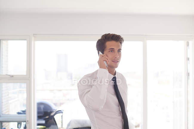 Бизнесмен в гостиной делает звонок по смартфону — стоковое фото