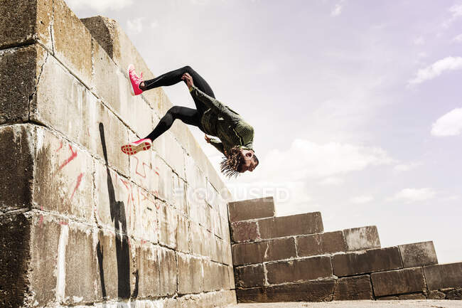 Young man somersaulting from side of wall — Stock Photo