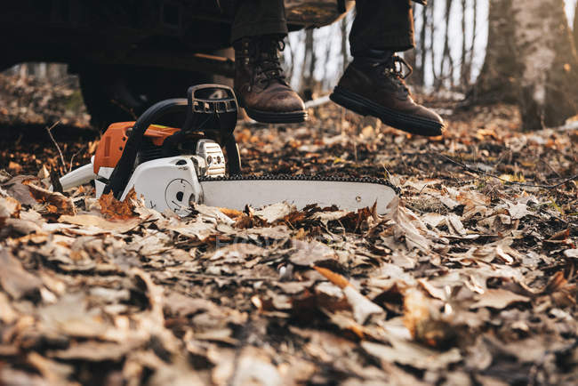 Homem de botas e motosserra na floresta de outono — Fotografia de Stock