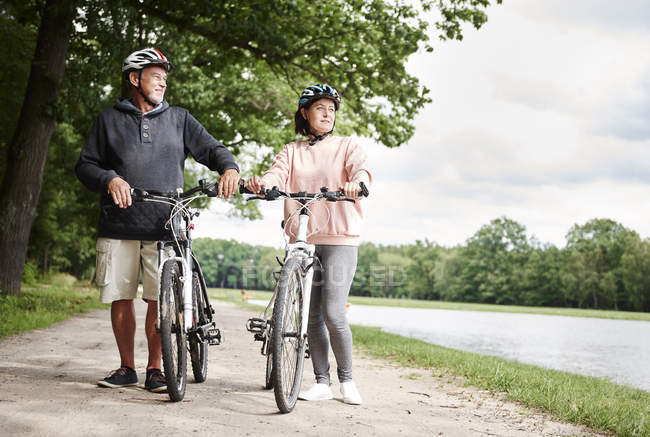 Couple mature marchant le long du chemin rural avec des vélos — Photo de stock