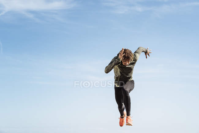 Young man running and jumping mid air outdoors — Stock Photo