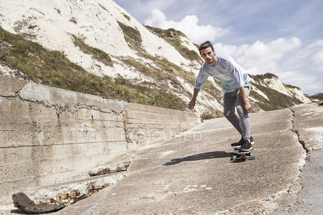 Jovem skate masculino perto da parede do mar — Fotografia de Stock