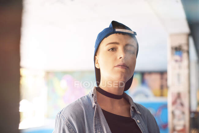 Ritratto di giovane skateboarder donna con berretto da baseball e fumare allo skateboard park — Foto stock