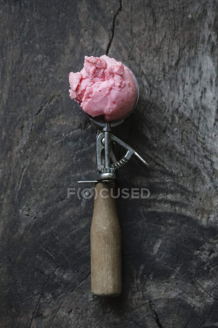 Ice cream in ice cream scoop on wooden surface — Stock Photo