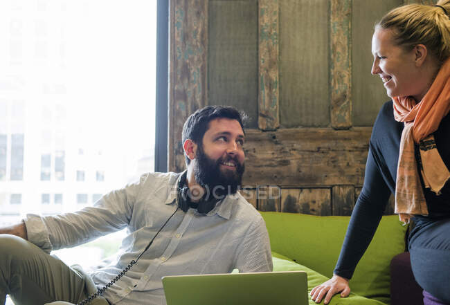 Colleagues on sofa using laptop chatting — Stock Photo
