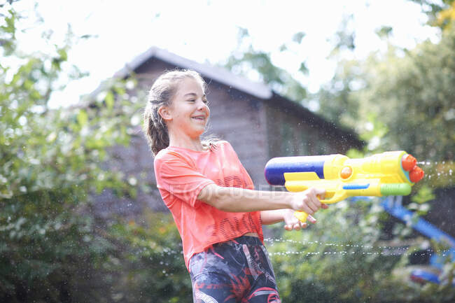 Adolescente éjacule pistolet à eau dans le jardin — Photo de stock