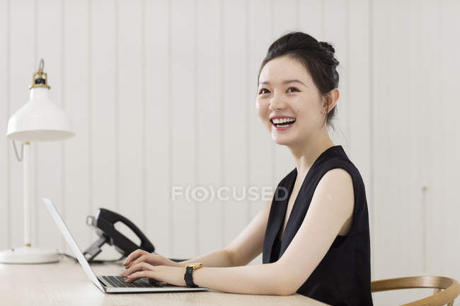 Молода жінка працює на ноутбуці за столом — стокове фото