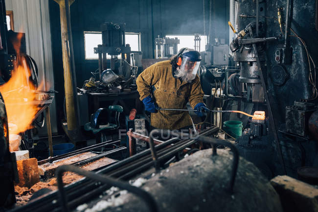 Schmied formt in Werkstatt heißen Metallstab — Stockfoto
