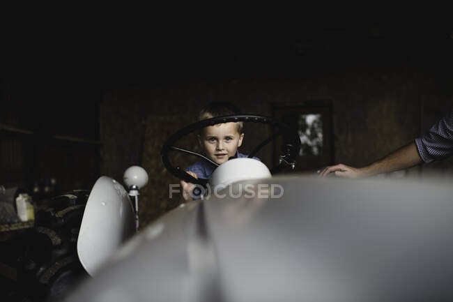 Boy on tractor holding steering wheel looking at camera — Stock Photo