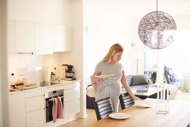 Вагітна молода жінка кладе обідній стіл — стокове фото