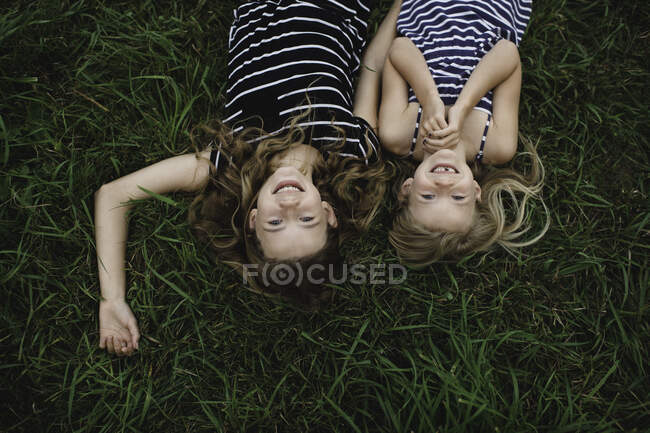 Overhead capovolto ritratto di ragazza e sua sorella sdraiata sull'erba — Foto stock