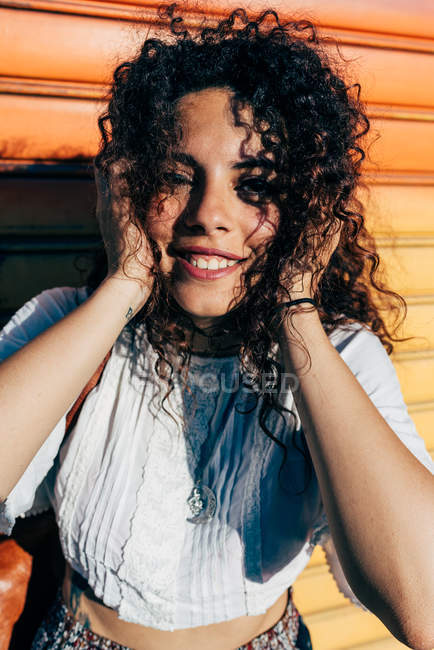 Retrato de jovem mulher encaracolada sorrindo para a câmera — Fotografia de Stock