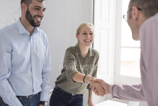 Uomo e donna d'affari che si stringono la mano al tavolo della sala riunioni — Foto stock