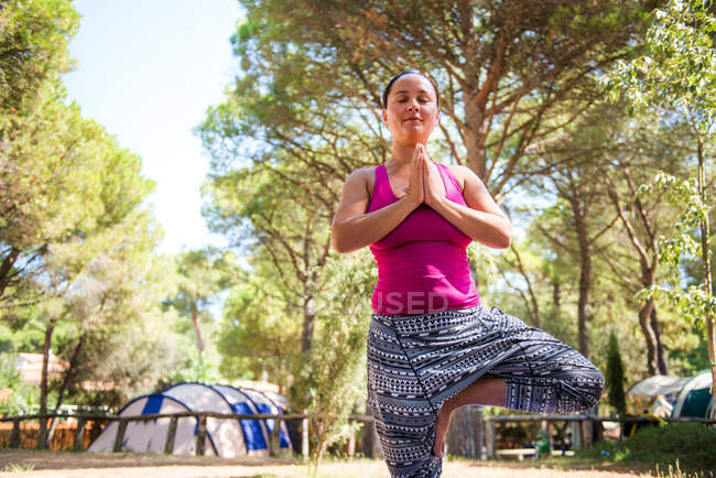 Mulher madura praticando ioga árvore pose no local de acampamento — Fotografia de Stock