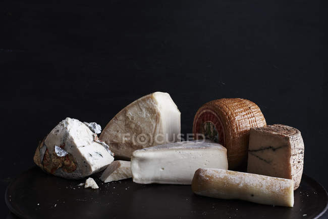 Auswahl an Käse auf schwarzem Teller vor schwarzem Hintergrund, Nahaufnahme — Stockfoto