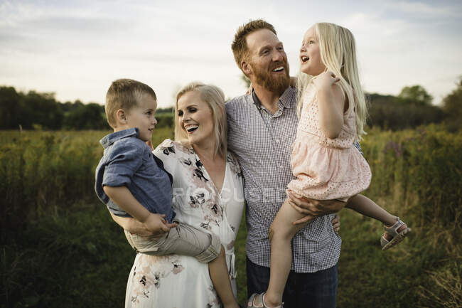 Smiling parents holding children in rural area — Stock Photo