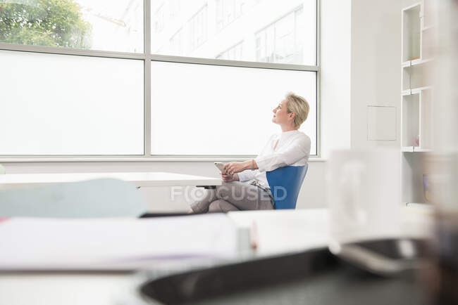 Frau blickt in Gedanken aus dem Bürofenster — Stockfoto