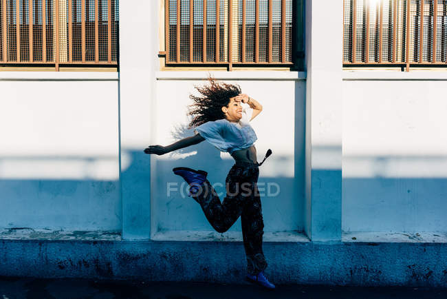 Mujer joven saltando cerca de la pared, Milán, Italia - foto de stock