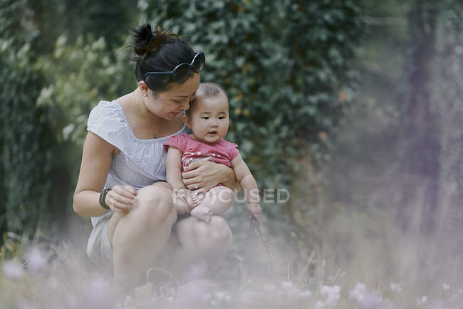 Mujer agachada con su hija en el parque - foto de stock
