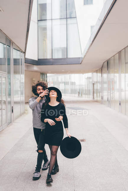 Jovem casal andando em ambiente urbano, brincando, rindo — Fotografia de Stock