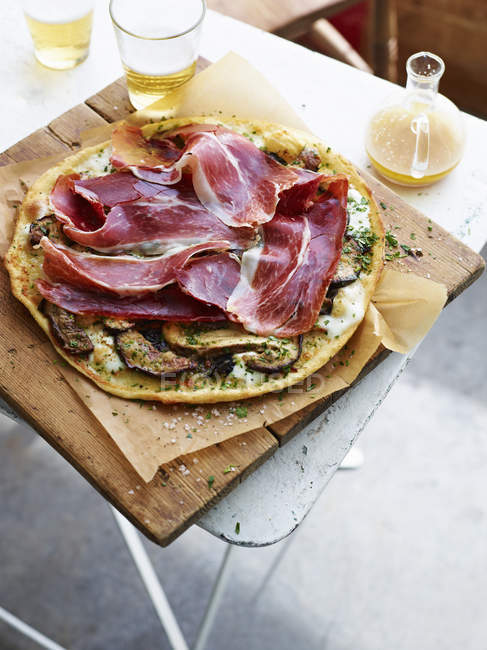 Porcini and prosciutto pizza on serving board — Stock Photo