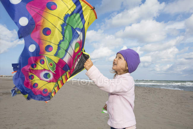 Menina com pipa voadora colorida na praia — Fotografia de Stock