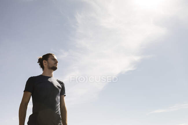 Jovem corredor masculino olhando contra o céu azul — Fotografia de Stock
