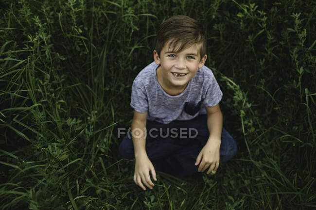 Boy looking up at camera on green grassy field — Stock Photo