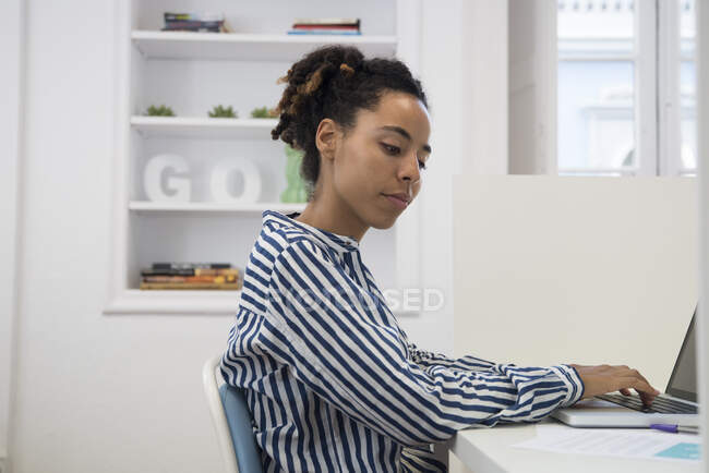 Mujer de negocios escribiendo en el ordenador portátil en el escritorio de la oficina - foto de stock