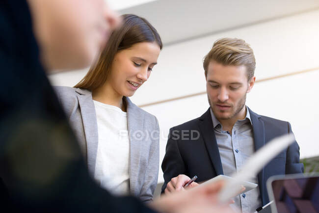 Junge Geschäftsfrau und Mann mit digitalem Tablet am Vorstandstisch — Stockfoto