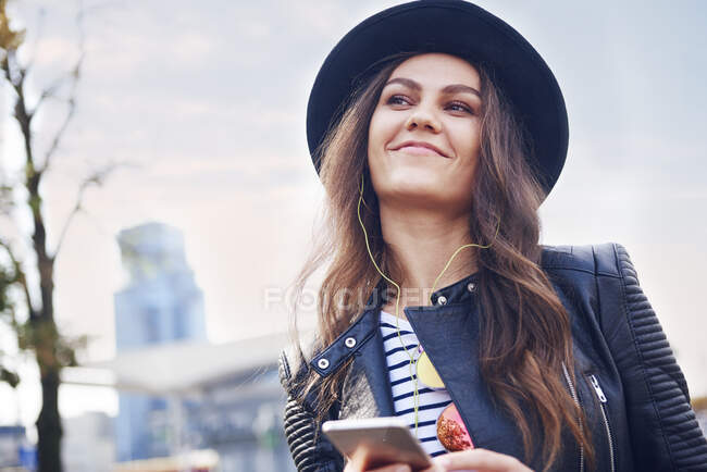 Portrait of young woman in trilby hat in city — Stock Photo