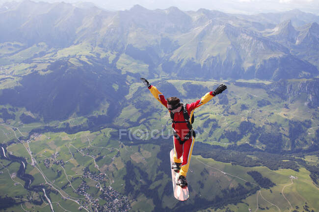 High angle view of skydiver surfing on sky board over mountains — Stock Photo