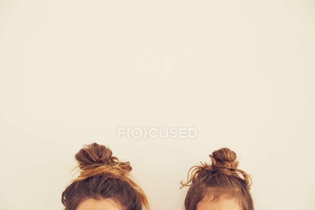Portrait of mother and daughter, hair in bun, top section — Stock Photo