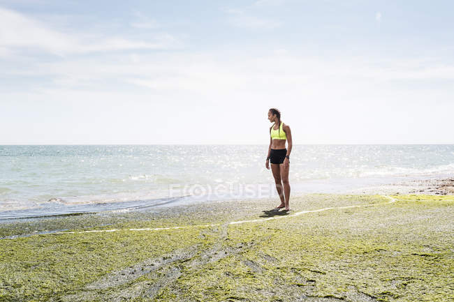 Junge erwachsene Frau in Sportkleidung gegen das Meer — Stockfoto