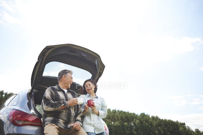 Mature couple near car holding tin cups — Stock Photo