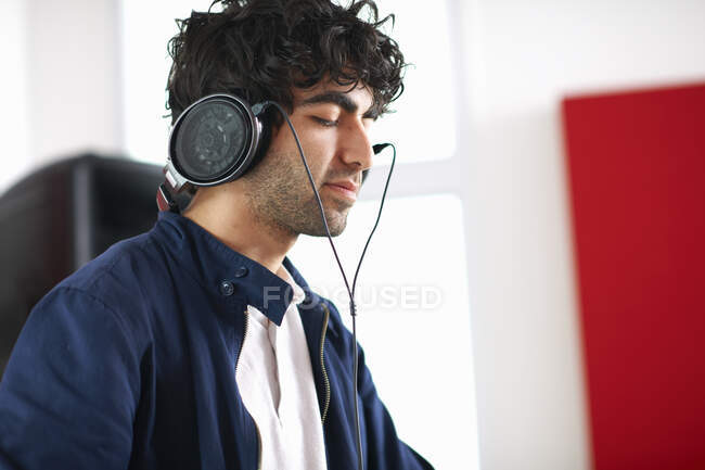 Joven estudiante de DJ universitario escuchando música en auriculares - foto de stock