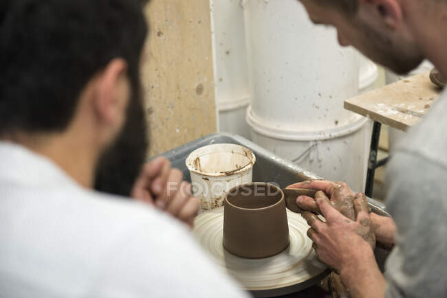 Tutor and student in art studio using pottery wheel — Stock Photo