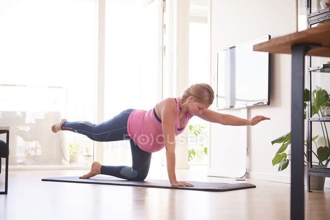 Jovem grávida fazendo exercício de ioga na sala de estar — Fotografia de Stock