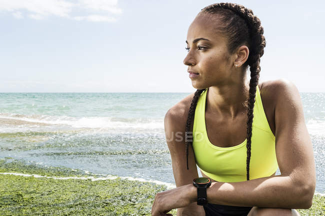 Jovem mulher adulta vestindo roupas esportivas contra o mar — Fotografia de Stock