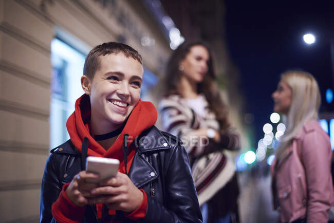Junge Frau mit Smartphone lacht nachts auf der Straße — Stockfoto