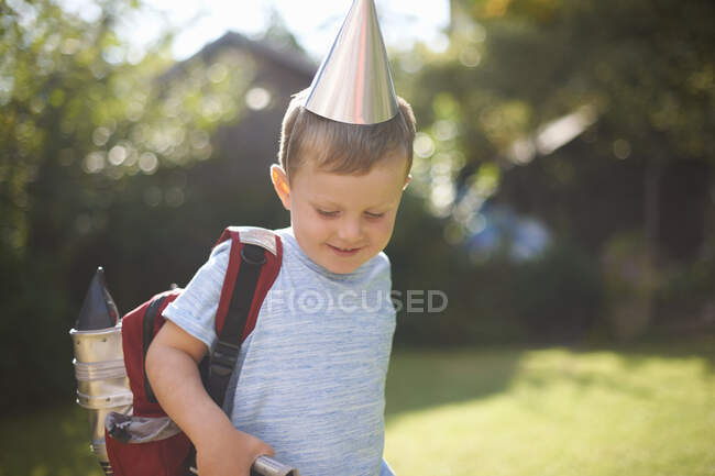 Happy boy in rocket costume and backpack in garden — Stock Photo