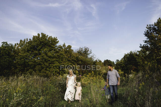 Família caminhando na grama alta juntos — Fotografia de Stock