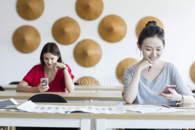 Estudantes usando telefone celular enquanto esperam na aula — Fotografia de Stock