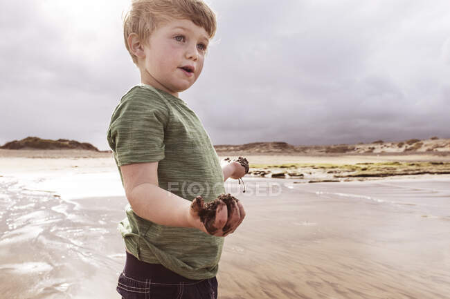 Niño en la playa, sosteniendo arena mojada, Santa Cruz de Tenerife, Islas Canarias, España, Europa - foto de stock