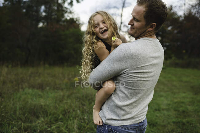 Padre e hija disfrutando al aire libre en campo de hierba verde - foto de stock