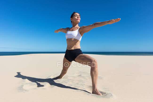 Femme sur la plage avec les bras ouverts étirement en position de yoga — Photo de stock
