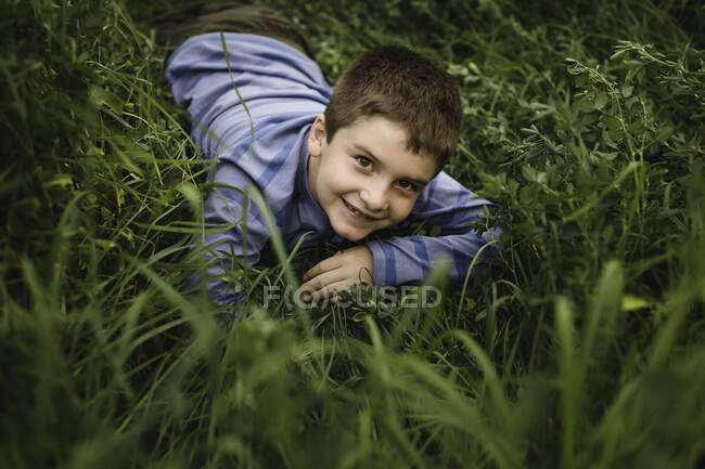 Мальчик смотрит в камеру на зеленом травянистом поле — стоковое фото