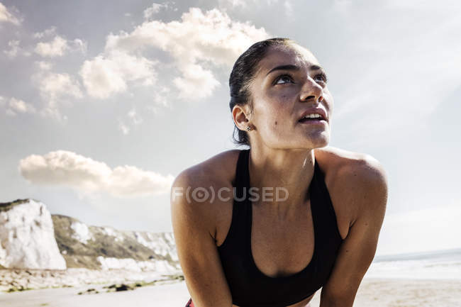 Виснажена молода жінка бігунка робить перерву на пляжі — стокове фото