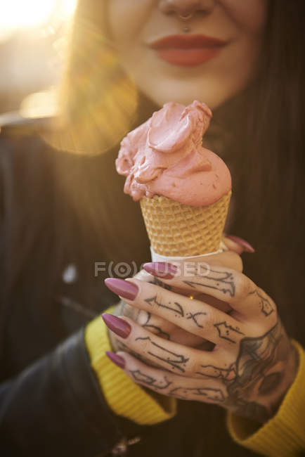 Young woman holding ice cream, tattoos on hand, mid section, close-up — Stock Photo