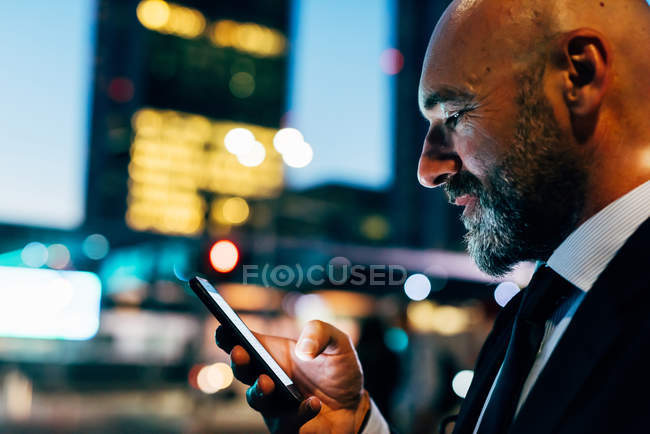 Uomo d'affari maturo utilizzando smartphone di notte — Foto stock